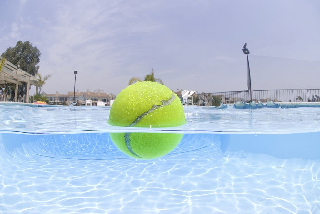 Une balle de tennis flottant dans une piscine.