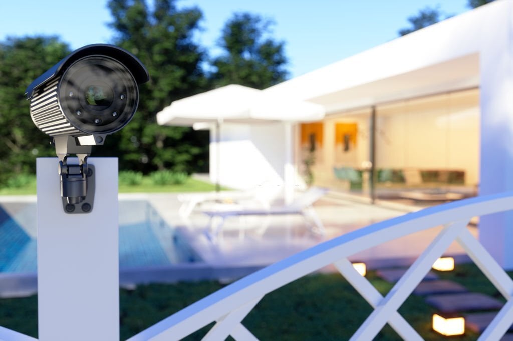 Une maison entourée de mesures de sécurité, y compris une alarme, des caméras de surveillance et des éclairages extérieurs.